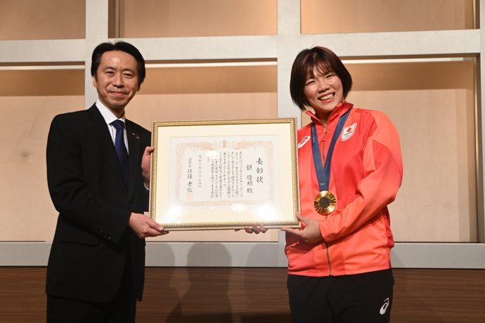 スポーツ栄誉賞の賞状を掲げる鏡選手と佐藤市長